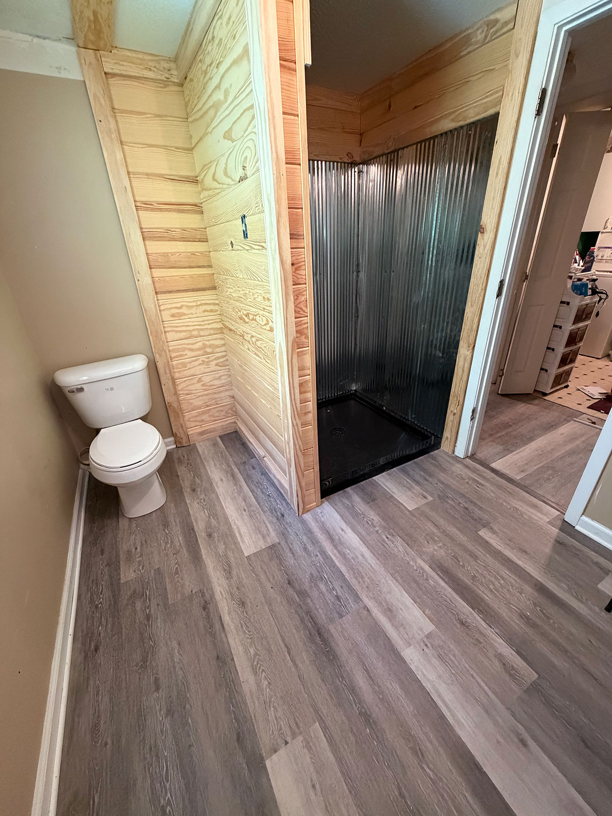 Remodeled bathroom with metal shower surround and luxury vinyl plank floor